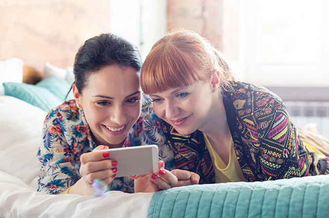 Two young women looking at a phone together and smiling.