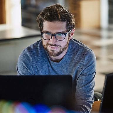 Young man with glasses looking at a computer.