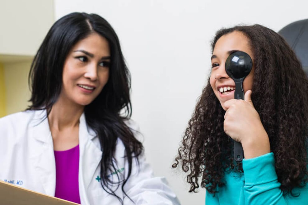 An optometrist administering a vision test for a young girl.